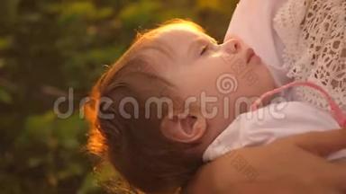 婴儿在夕阳的<strong>金色光</strong>芒中睡在母亲的怀里。 慢动作